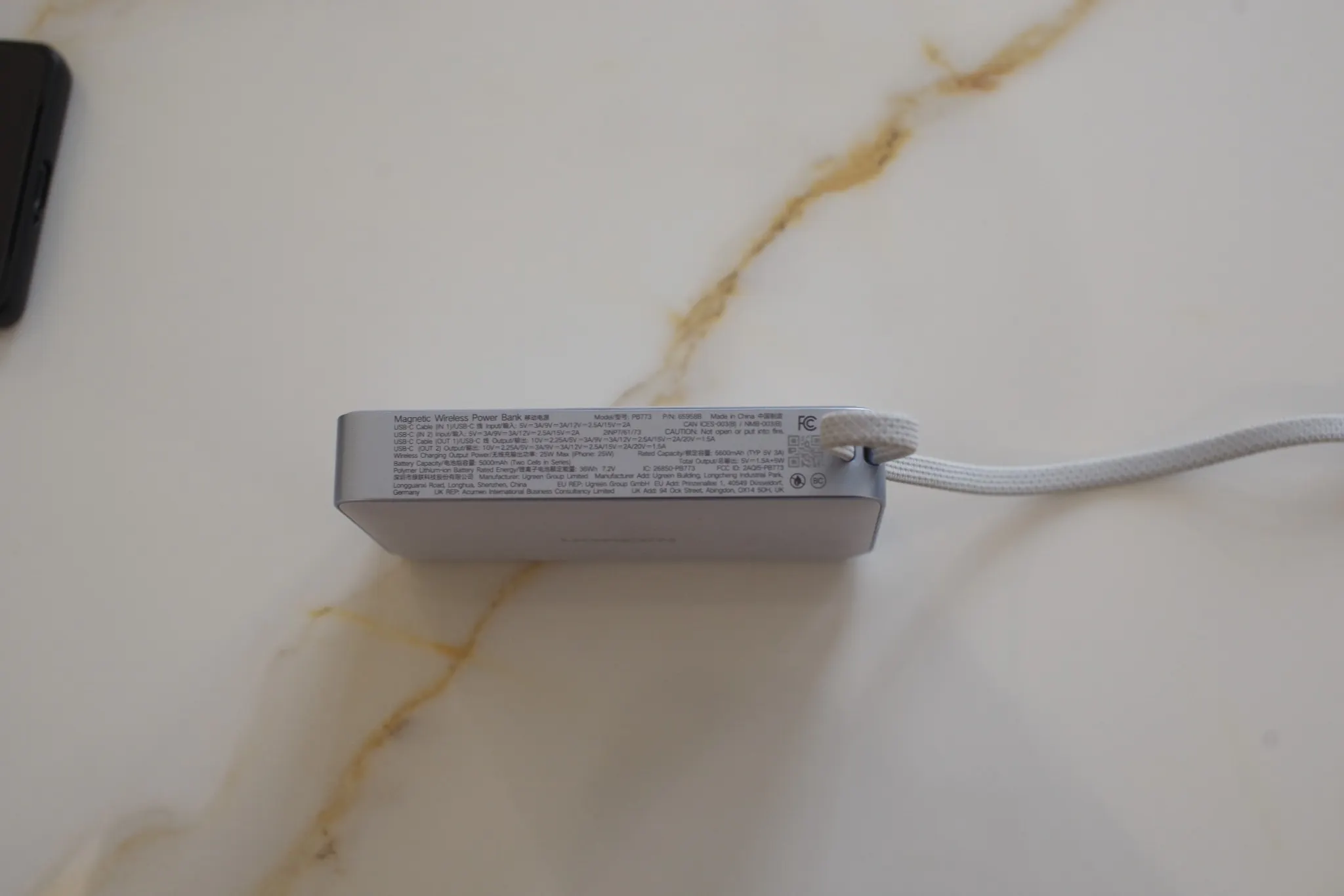 Side view of UGREEN Qi2 magnetic power bank attached beneath a phone